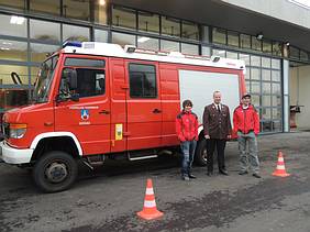 Bergretter und Feuerwehrmann mit Feuerwehrauto vor dem neuen Einsatzzentrum