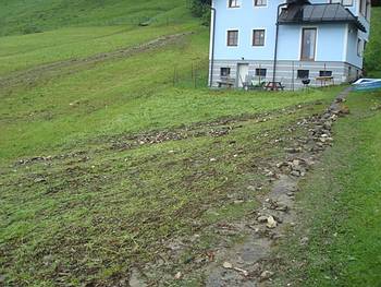 der verklauste Bach mit Ger�ll und Schlamm sucht sich den Weg �ber die Wiese